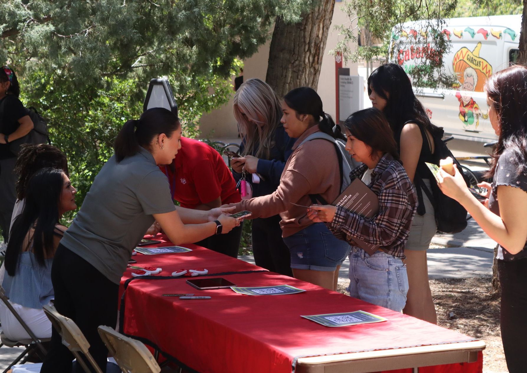 A group of people are standing around a table talking to each other.