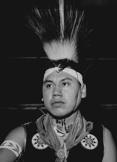 A black and white photo of a man wearing a headdress