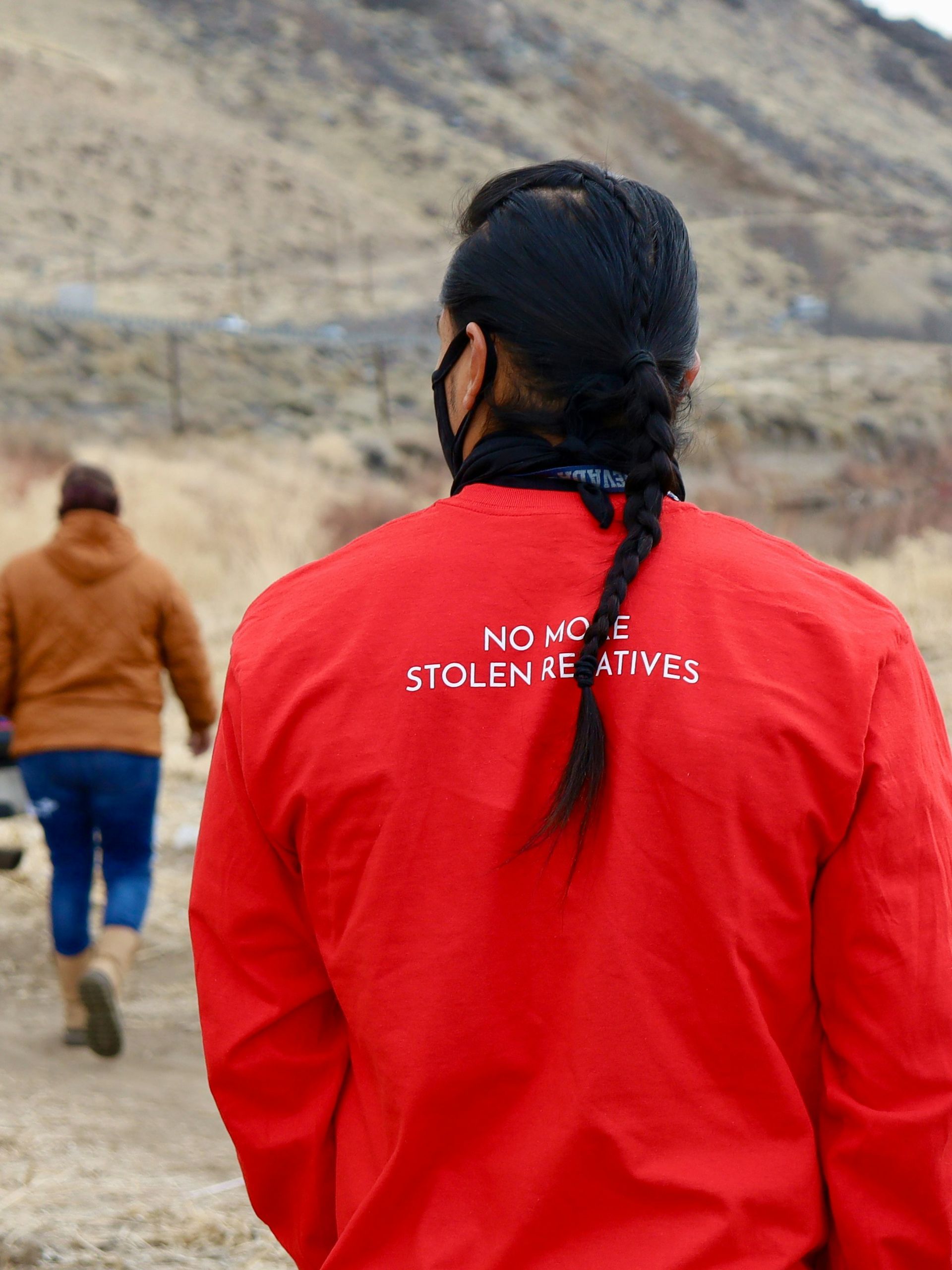 The back of a person wearing a red jacket that says no more stolen natives