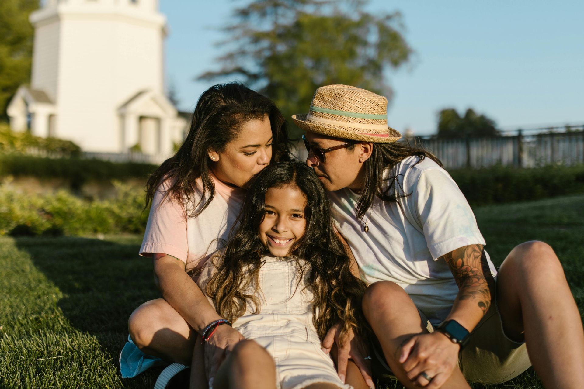 A man and two girls are sitting on the grass in a park.