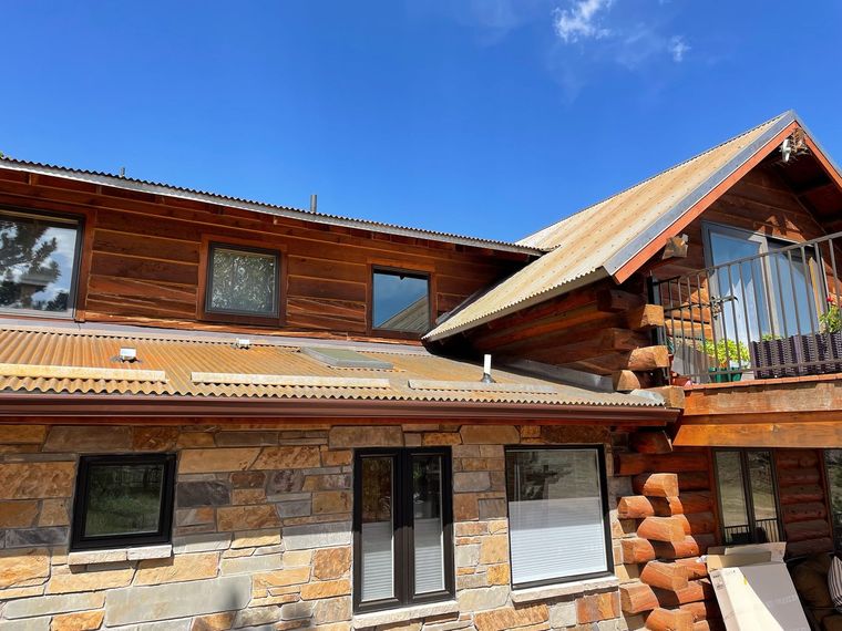 A large log cabin with a metal roof and a balcony.
