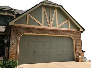 A brick house with a green garage door is being remodeled