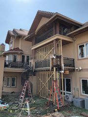 A large house is being remodeled with a balcony and stairs.