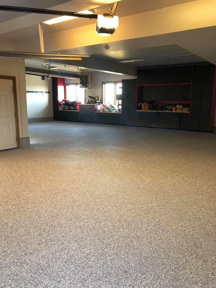 An empty garage with a garage door open and a carpeted floor.