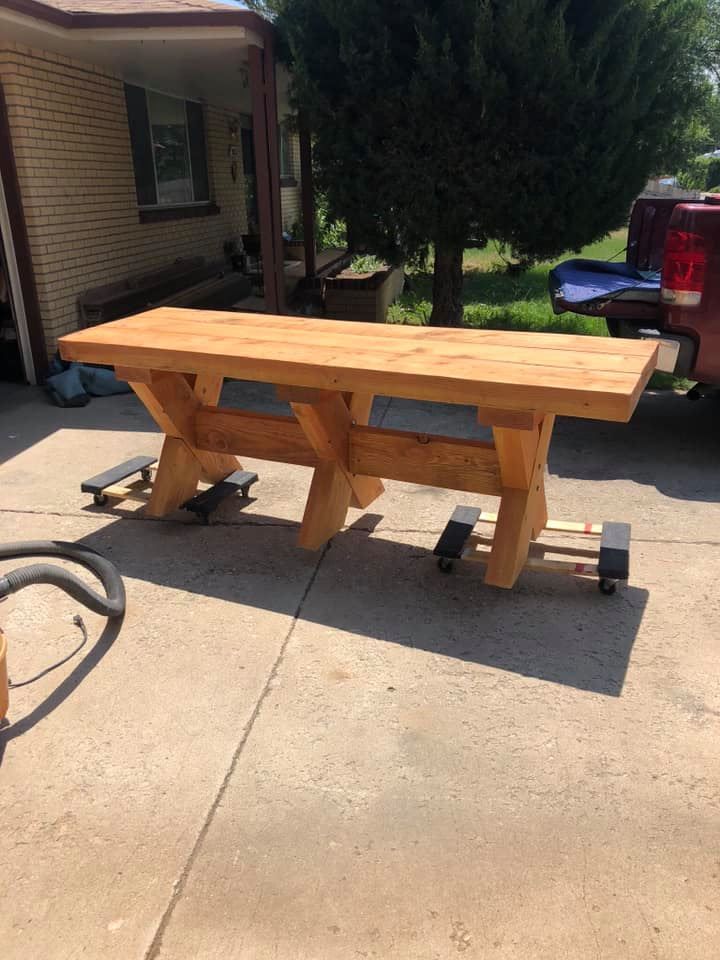 A wooden table is sitting in a driveway next to a truck.