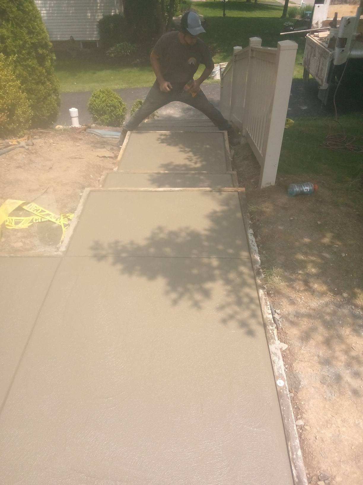 Man in gloves lays paving stones in layers on garden pathway – Rochester, PA - Luick & Sons Contracting Inc