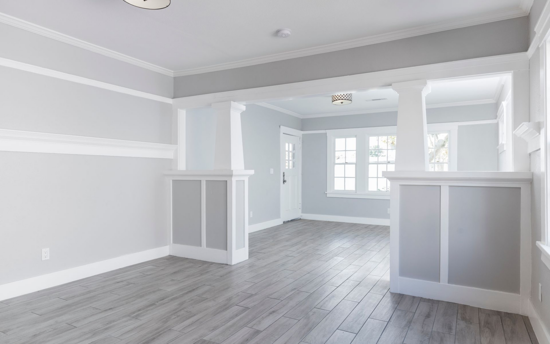 Empty interior with gray walls, white trim, and light gray wood flooring.