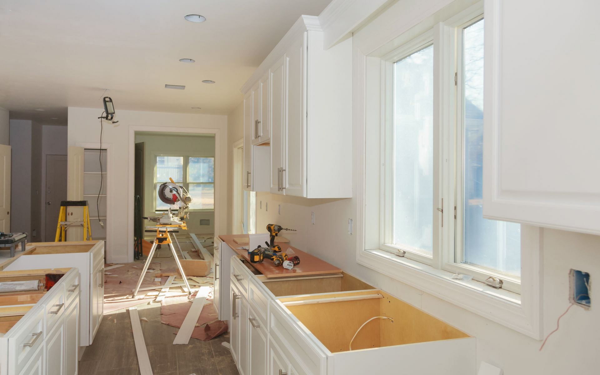 Kitchen under renovation with white cabinets, wood countertops, and a window.