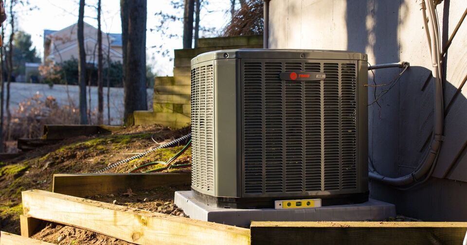A man in a red shirt is working on an air conditioner.