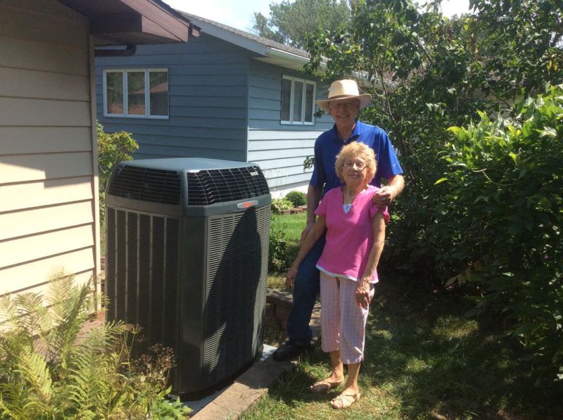 A man and woman standing in front of an air conditioner