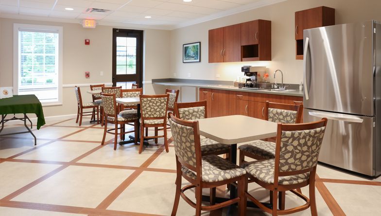 A room with tables and chairs and a stainless steel refrigerator