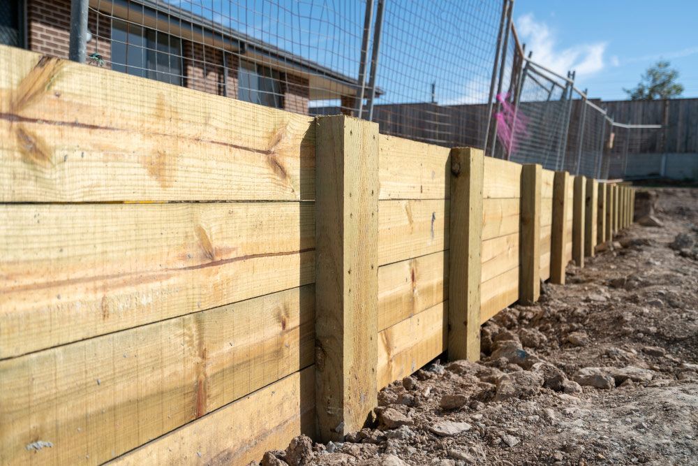 A Wooden Fence Is Being Built in A Dirt Field — Gnomes Landscape & Garden Supplies In Gloucester, NSW