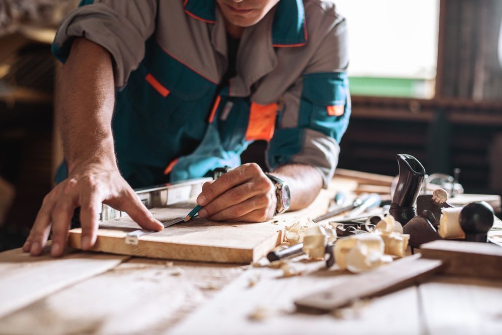 A Man Is Working on A Piece of Wood in A Workshop — Gnomes Landscape & Garden Supplies In Port Macquarie, NSW