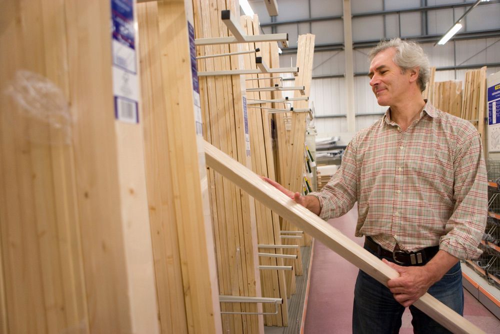 A Man Is Holding a Piece of Wood in A Store — Gnomes Landscape & Garden Supplies In Pacific Palms, NSW
