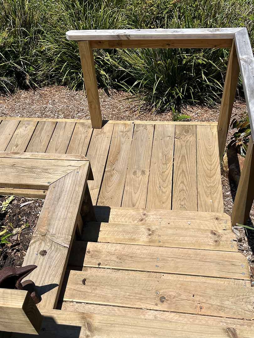 A Set Of Wooden Stairs With A Metal Railing Leading Up To A Garden — Gnomes Landscape & Garden Supplies In Forster, NSW