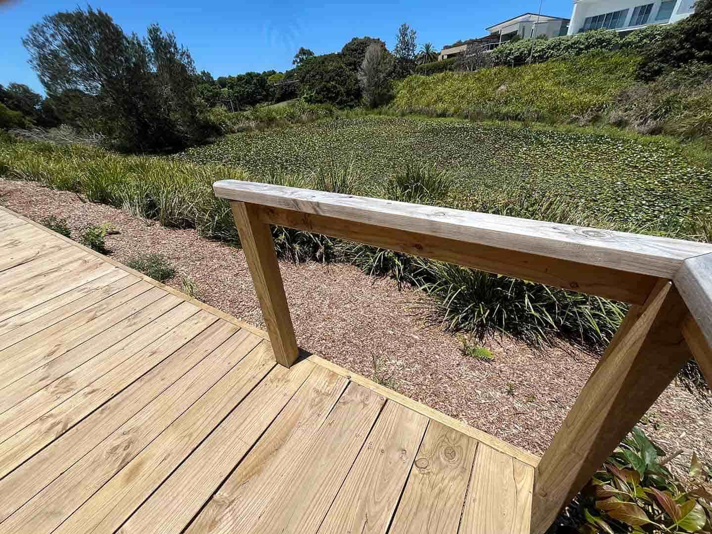 A Wooden Deck With A Railing Leading To A Grassy Field — Gnomes Landscape & Garden Supplies In Wingham, NSW