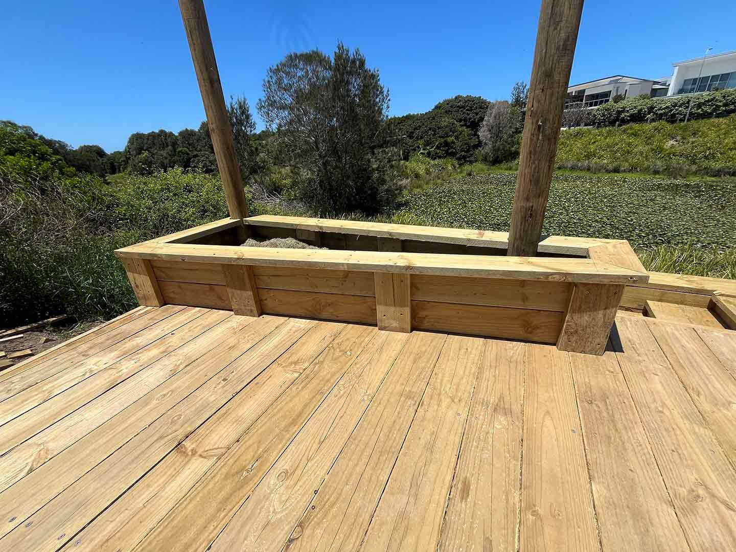A Wooden Deck With A Planter In The Middle Of It — Gnomes Landscape & Garden Supplies In Wingham, NSW
