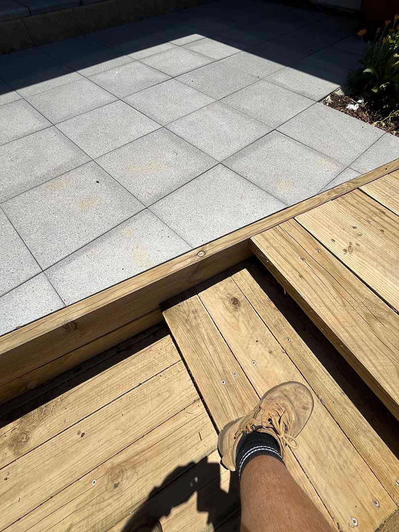 A Person Is Standing On A Wooden Deck Next To A Tiled Floor — Gnomes Landscape & Garden Supplies In Wauchope, NSW