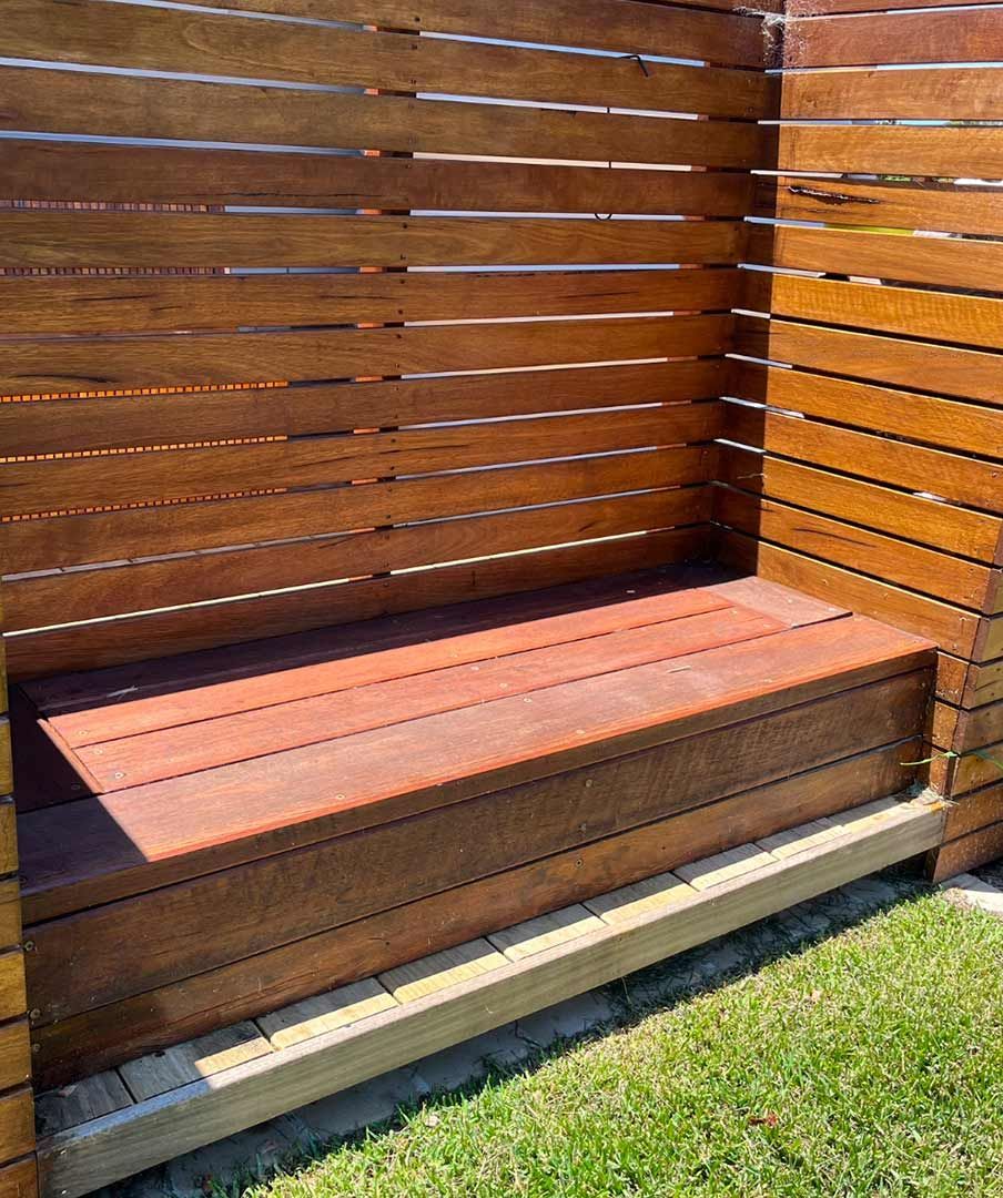 A Wooden Bench Is Sitting In The Grass Next To A Wooden Fence — Gnomes Landscape & Garden Supplies In Taree South, NSW