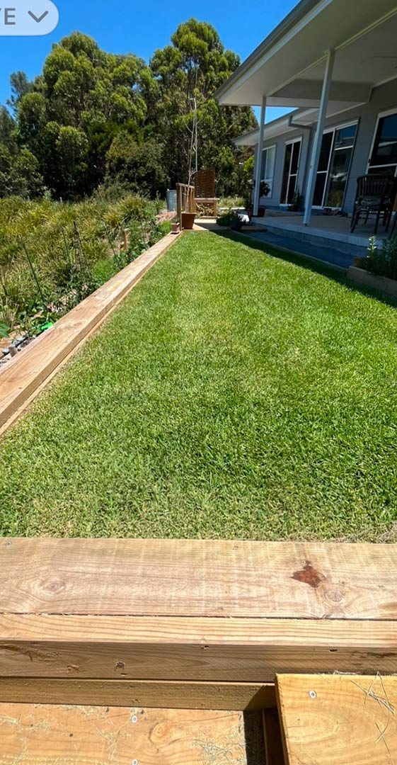 A Wooden Fence Surrounds A Lush Green Lawn In Front Of A House — Gnomes Landscape & Garden Supplies In Hallidays Point, NSW