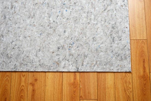 Close-up of thick area rug pads on hardwood flooring.