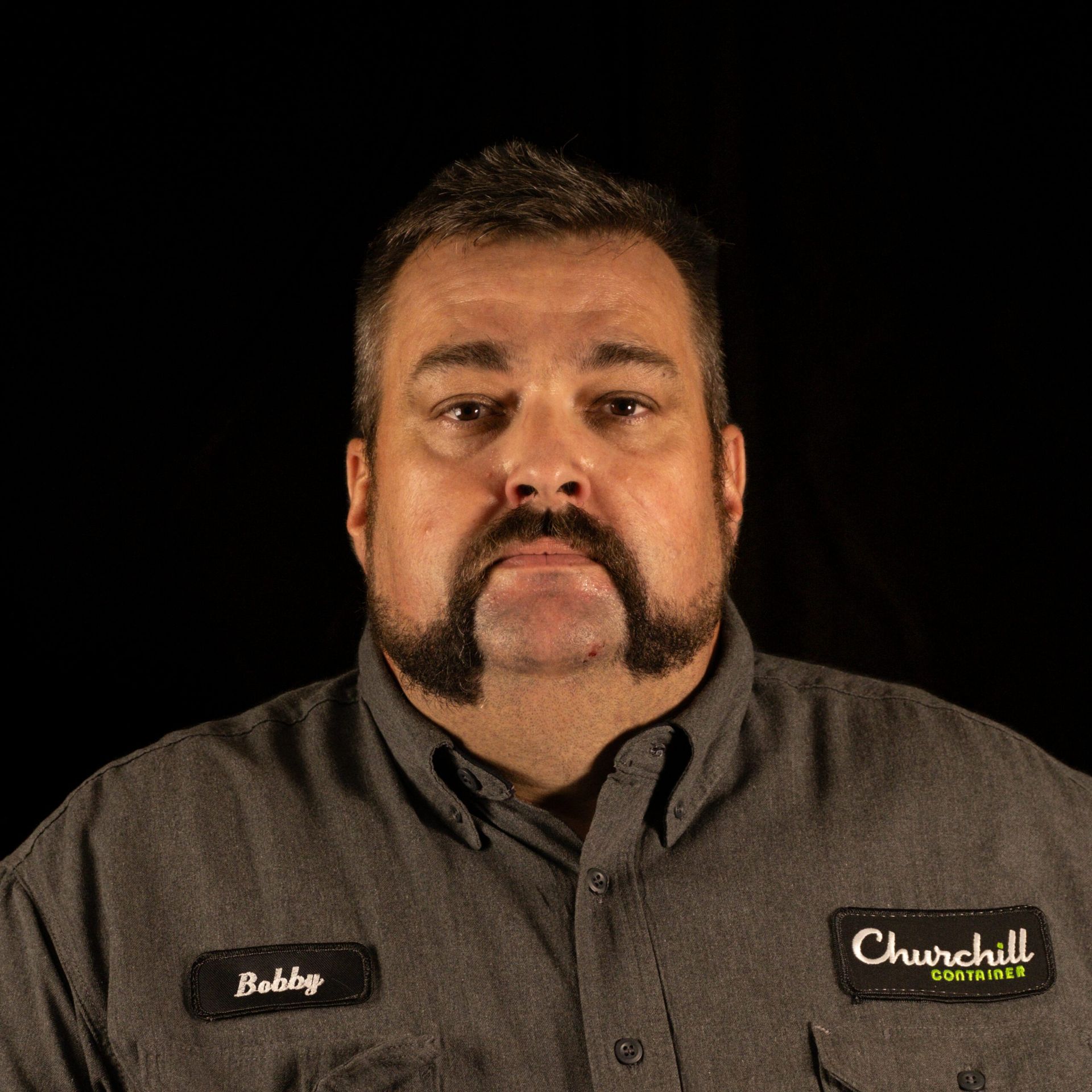 Man with a handlebar mustache in a grey shirt with 