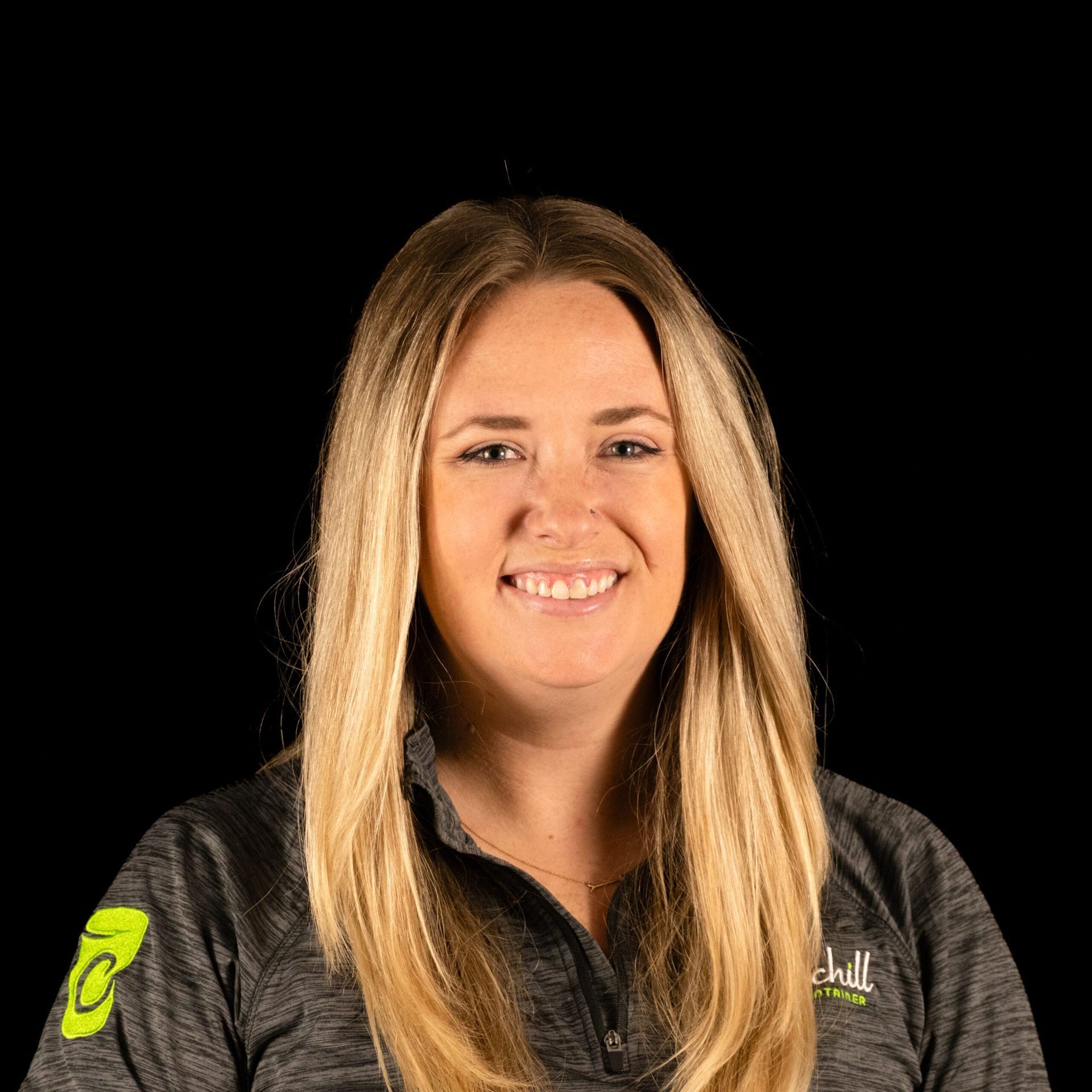 Woman with blonde hair smiling, wearing a gray polo shirt with a company logo.