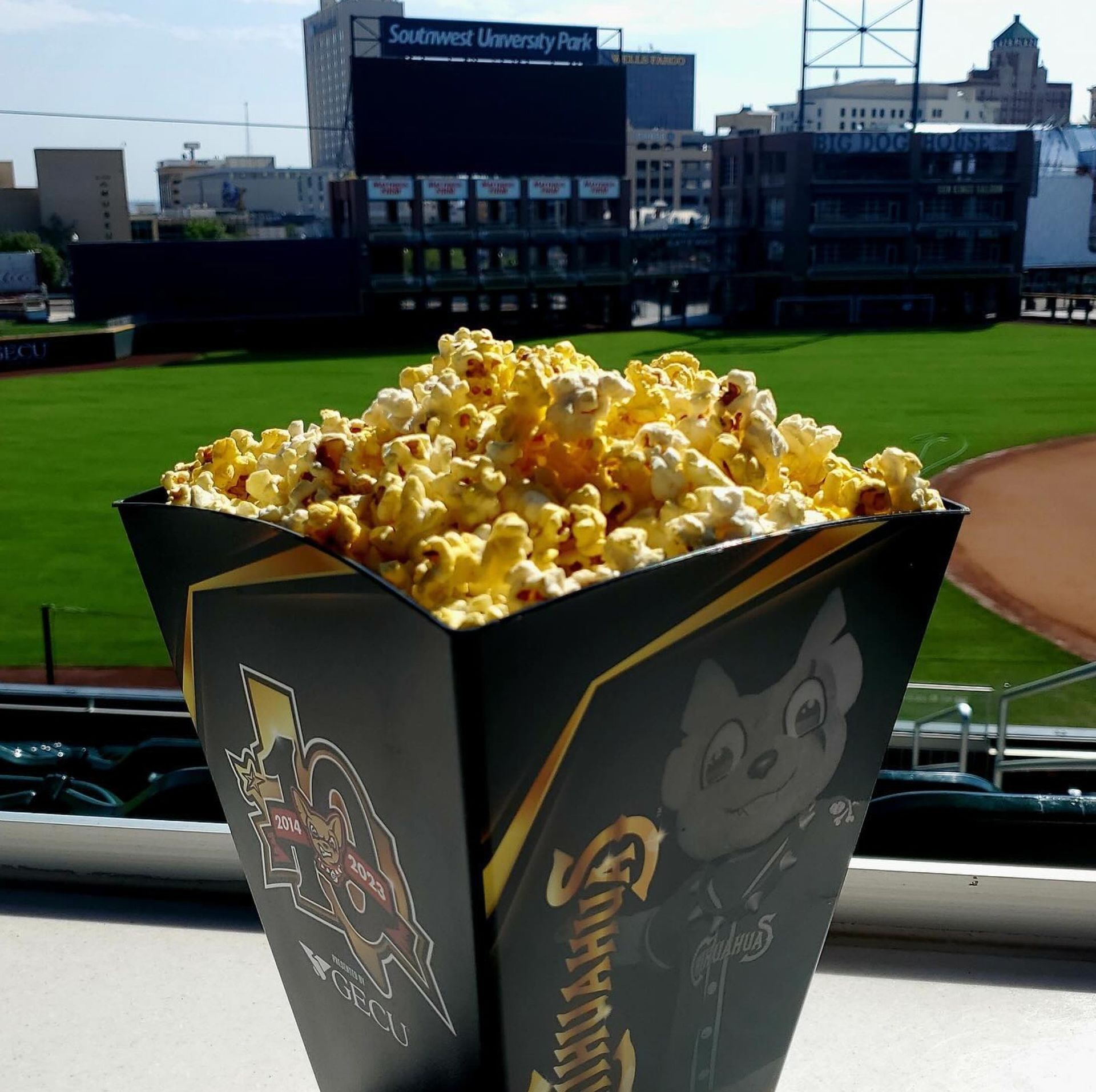 Popcorn in a branded cup at a baseball stadium.