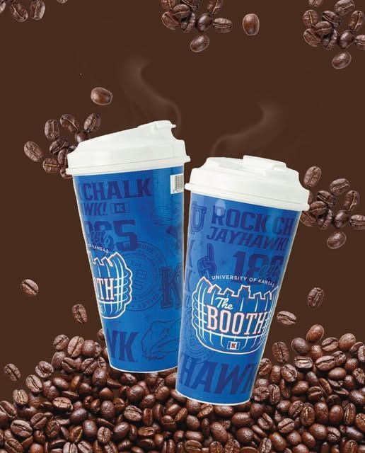 Two blue coffee cups with white lids, surrounded by coffee beans, steaming.