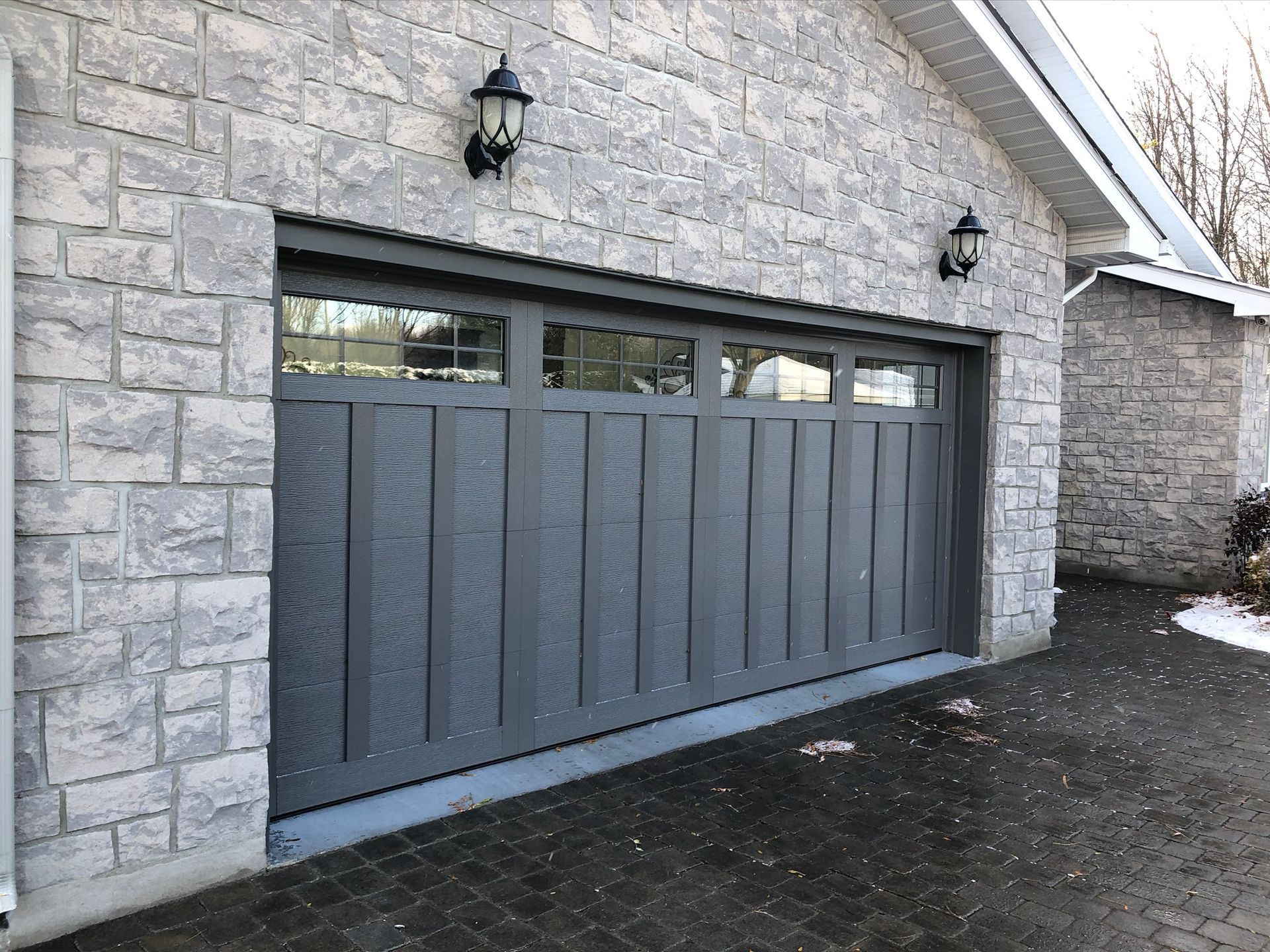 Une porte de garage grise se trouve sur le côté d'un bâtiment en briques.