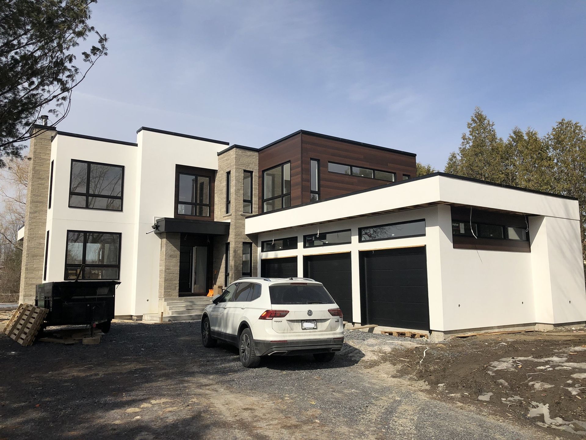 Une voiture blanche est garée devant une grande maison.