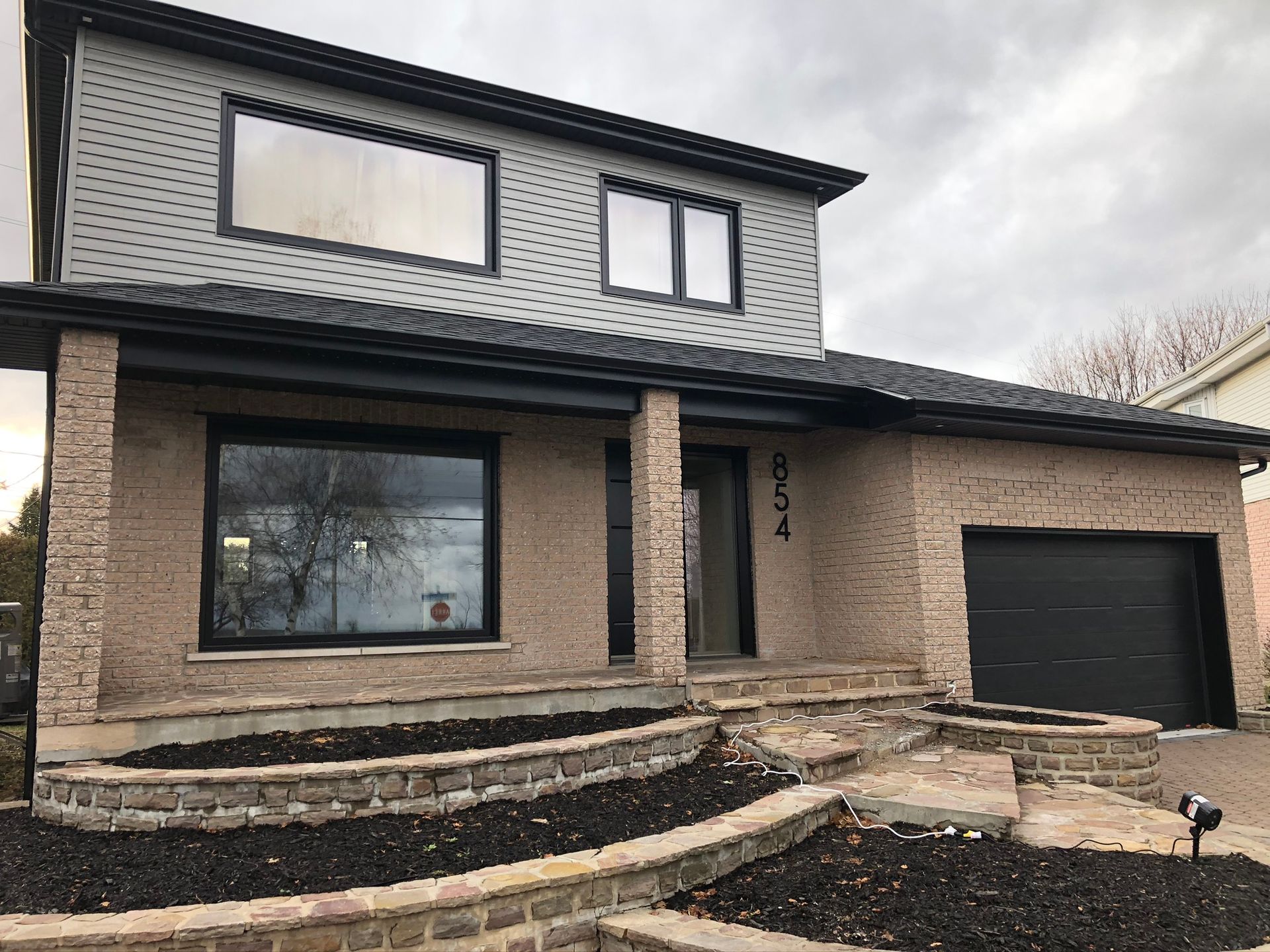 Une grande maison en briques avec une porte de garage noire.