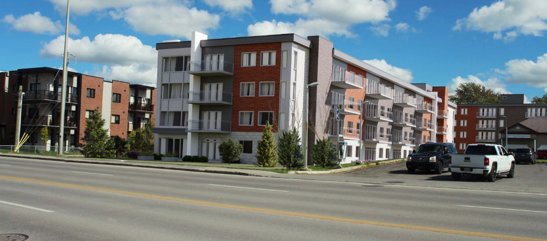 Apartment buildings with a blue sky and clouds. Vehicles parked on the side of the road.