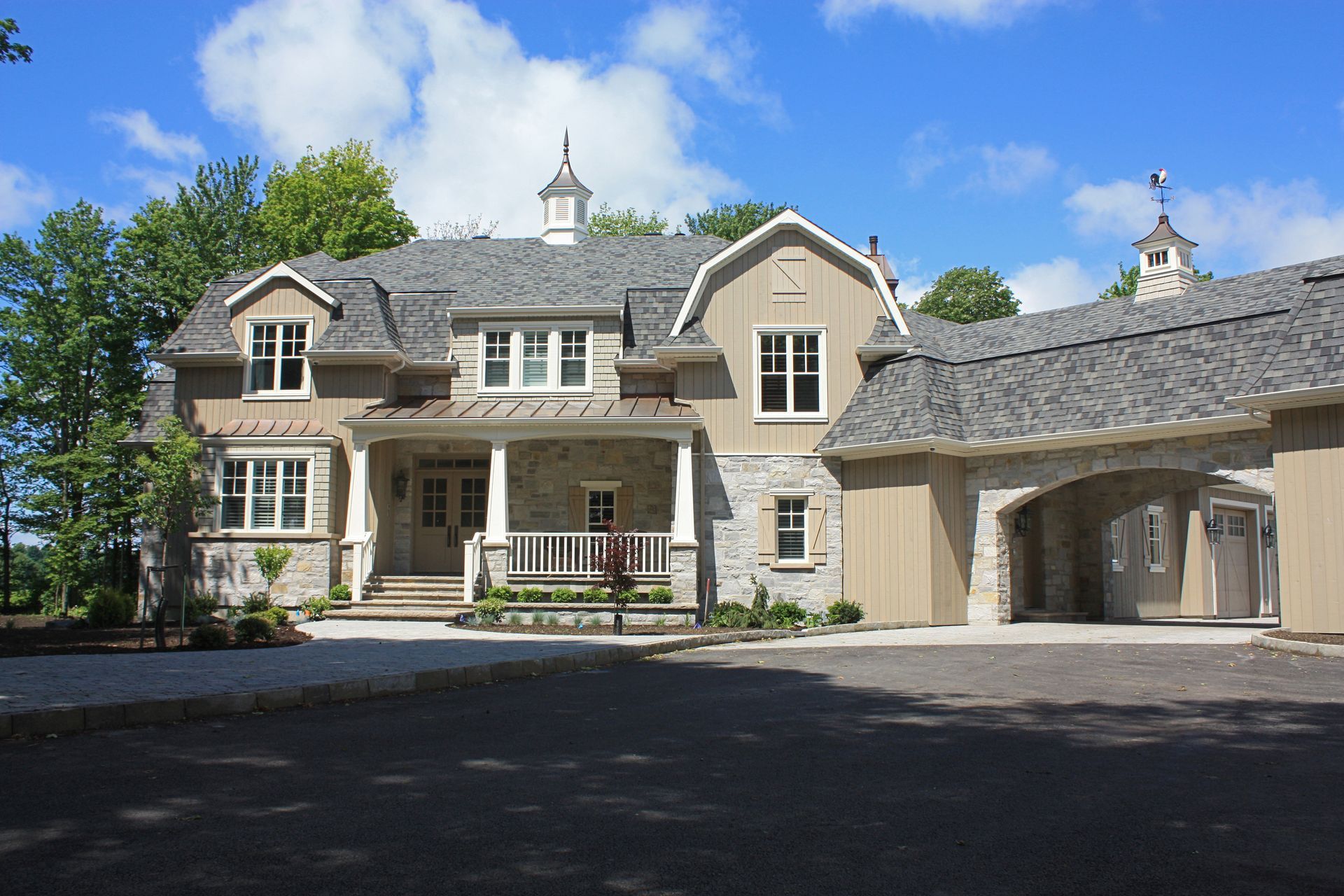 Une grande maison au toit gris est entourée d'arbres