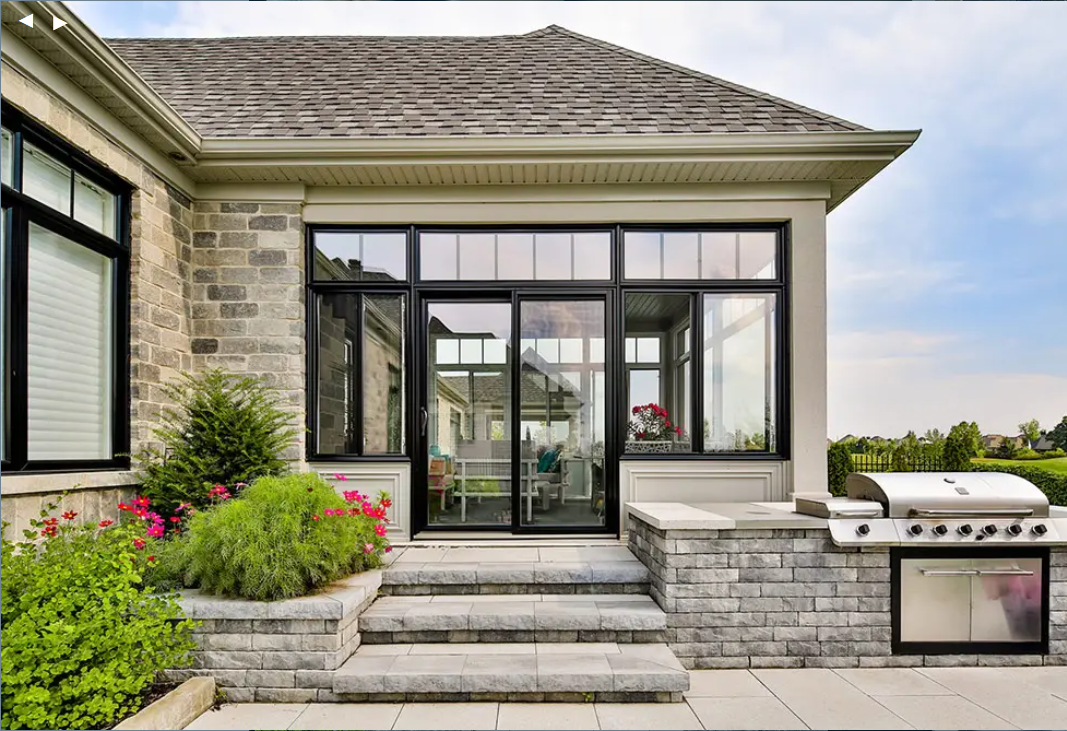 A large house with a sliding glass door and a grill in the backyard.
