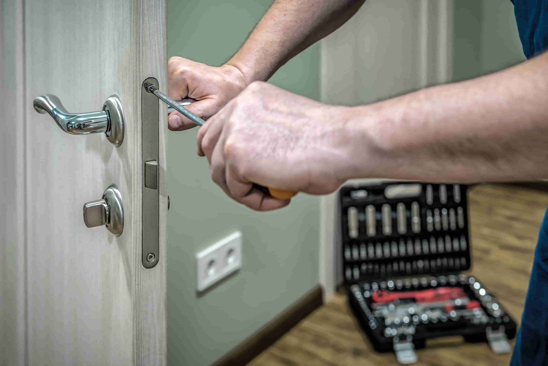 Person using a screwdriver to install a door lock; toolbox in the background - ADC Locksmiths in Wollongong, NSW