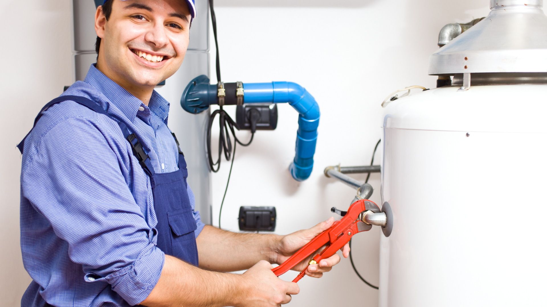A plumber is fixing a water heater with a wrench.