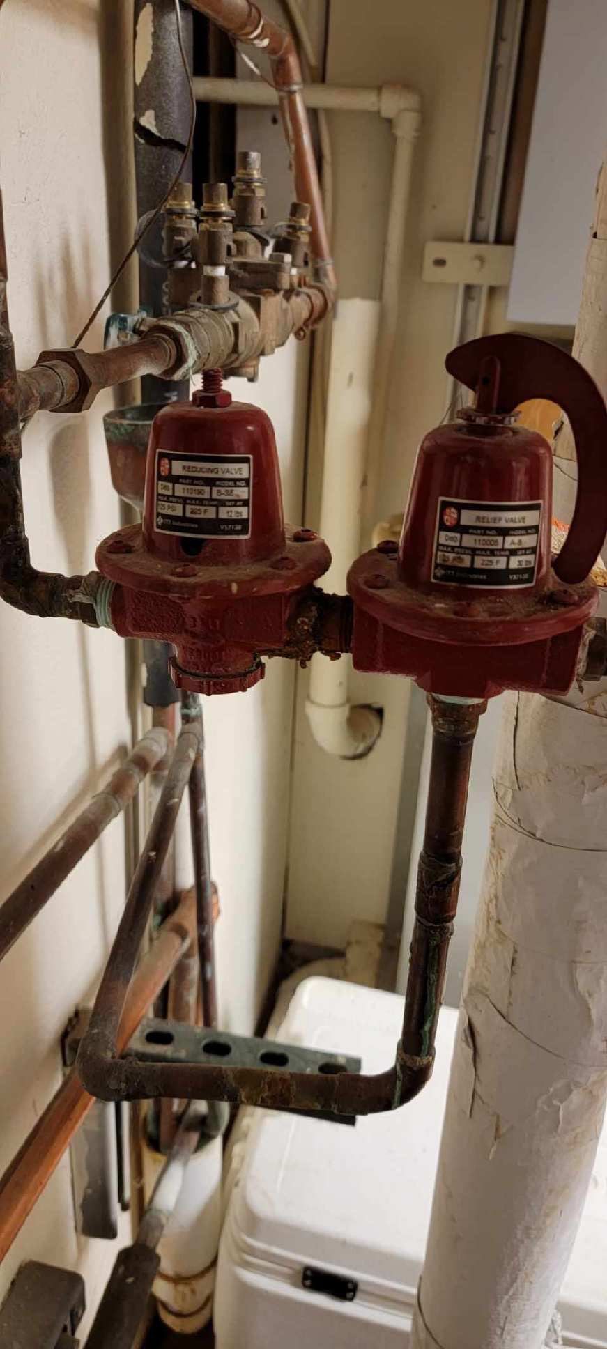 A room with a lot of pipes and valves on the wall.