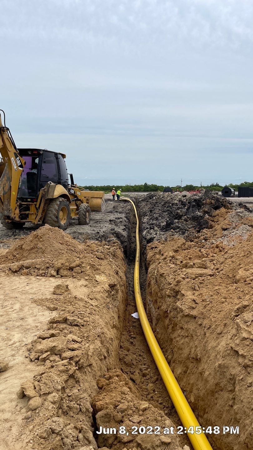 A yellow pipe is being installed in the dirt next to a bulldozer.