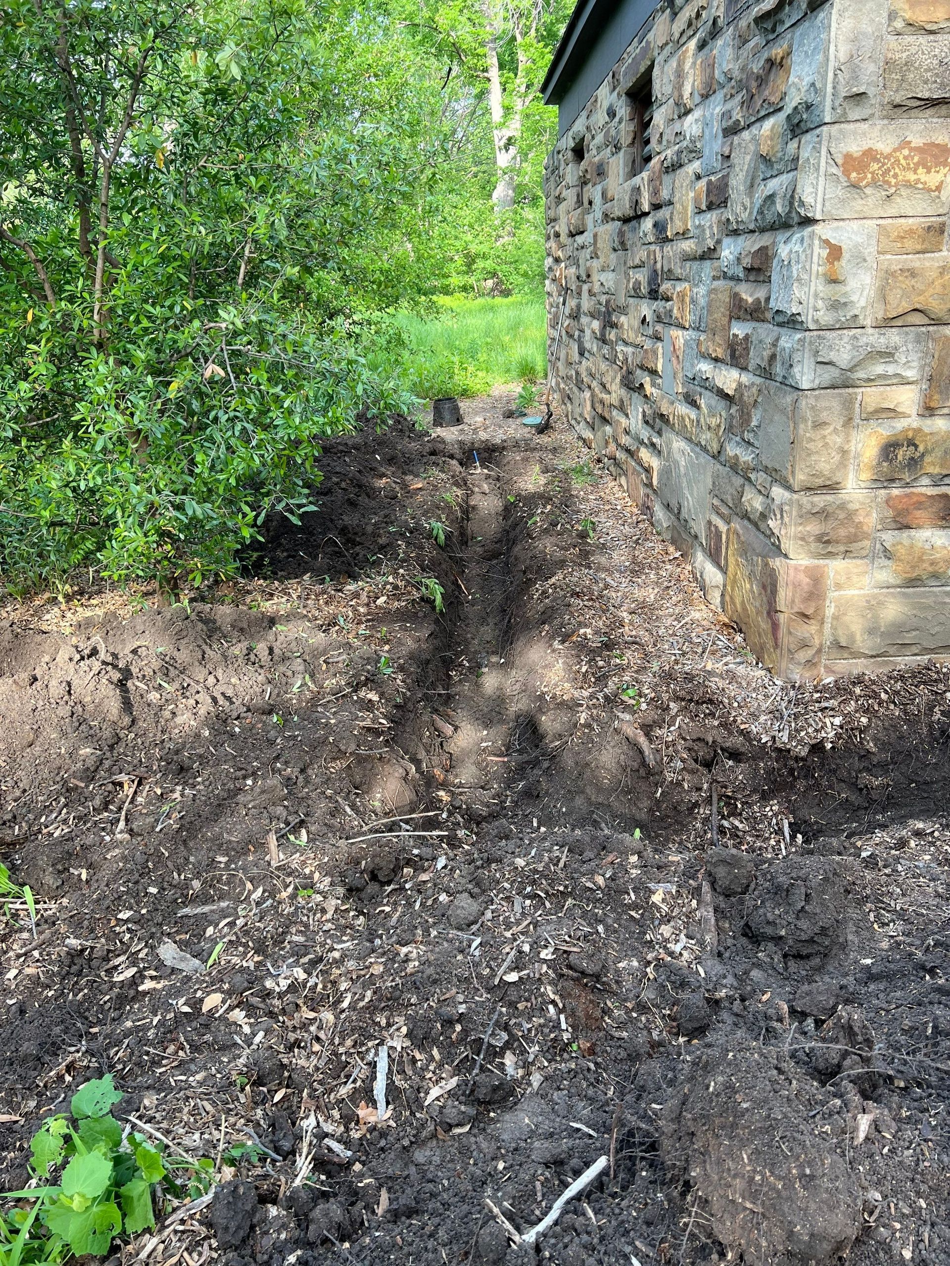 A pile of dirt is sitting next to a stone wall.