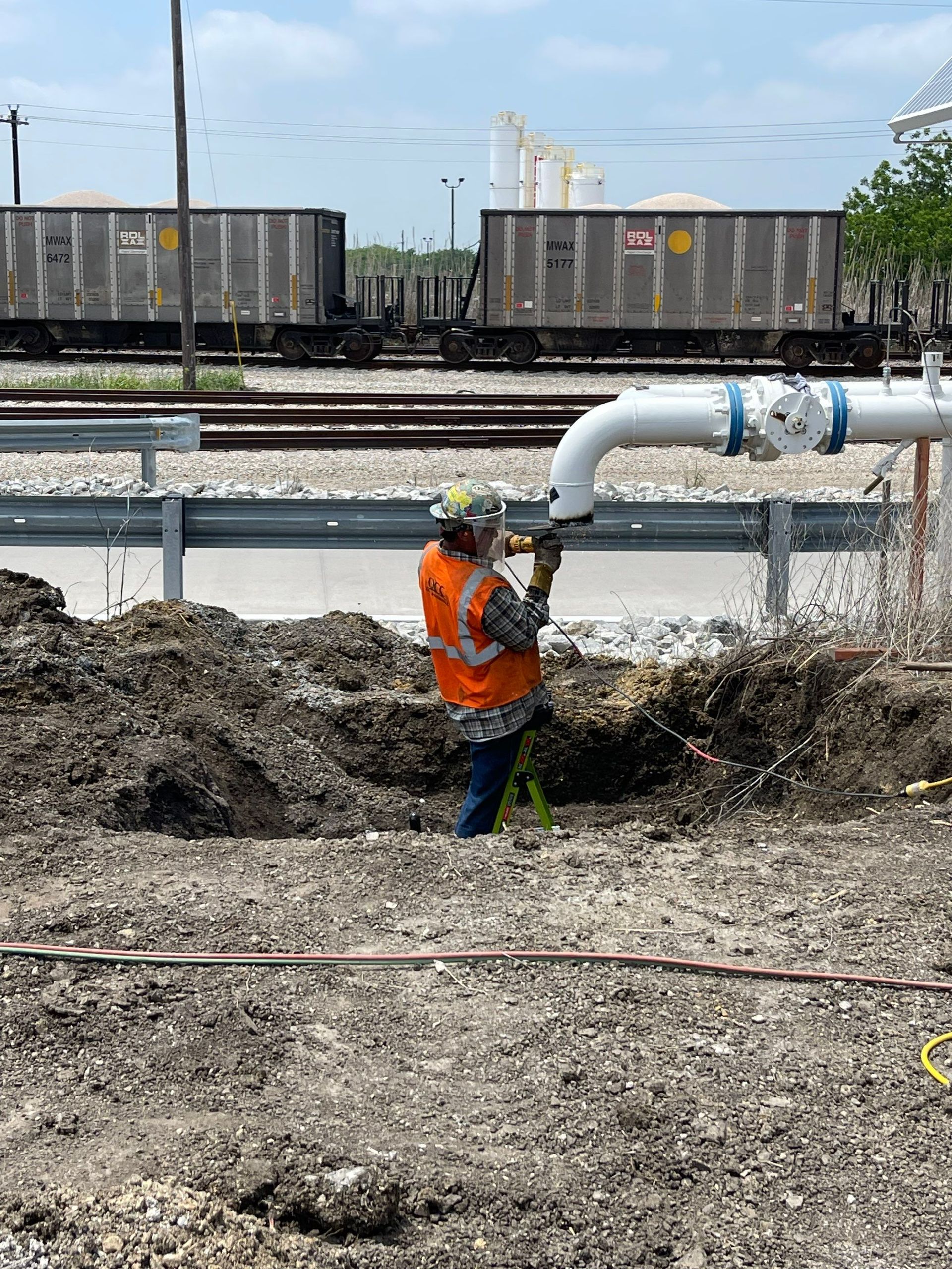 A man is working on a pipe in the dirt.