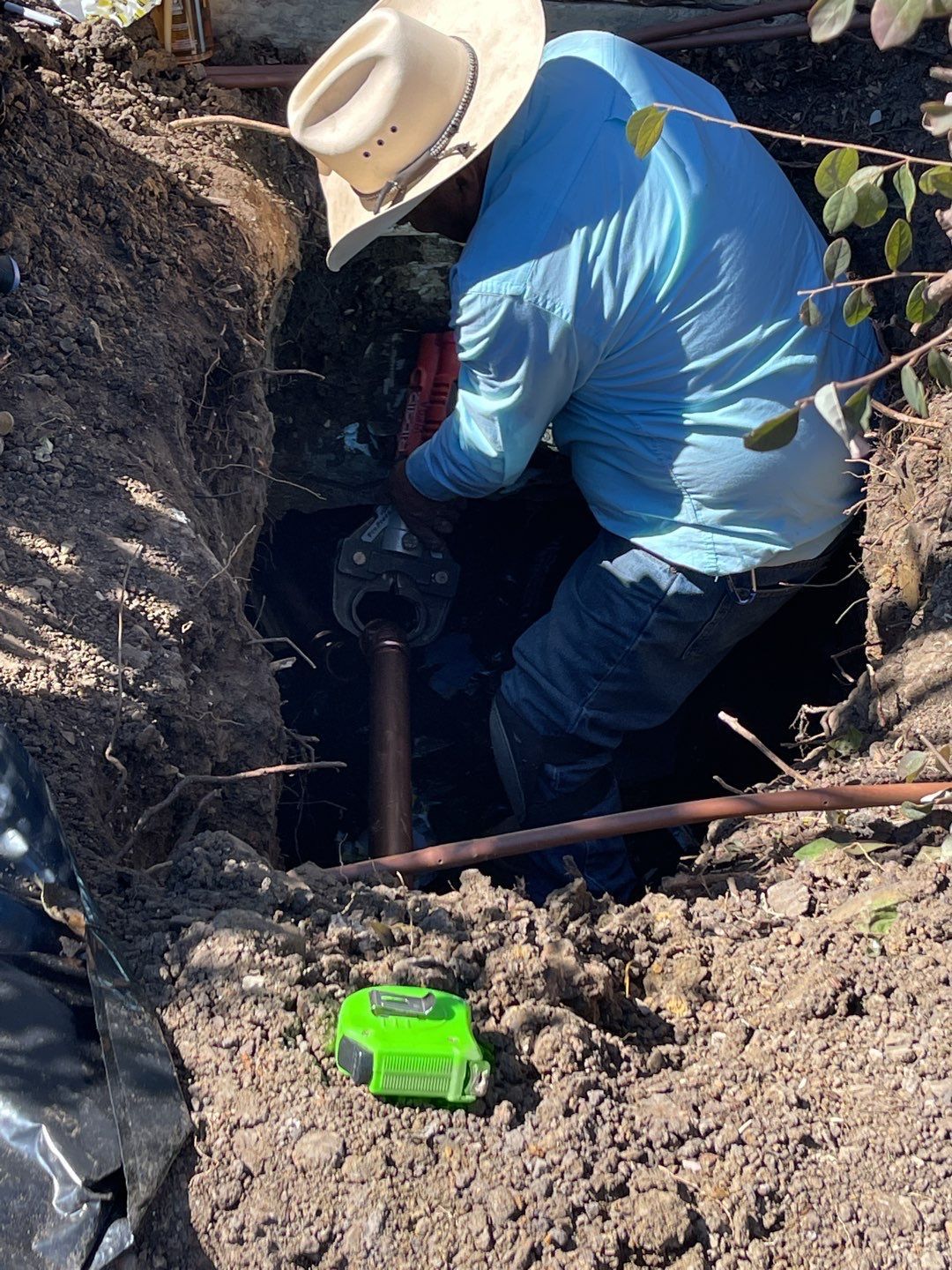 A man wearing a cowboy hat is digging a hole in the ground.