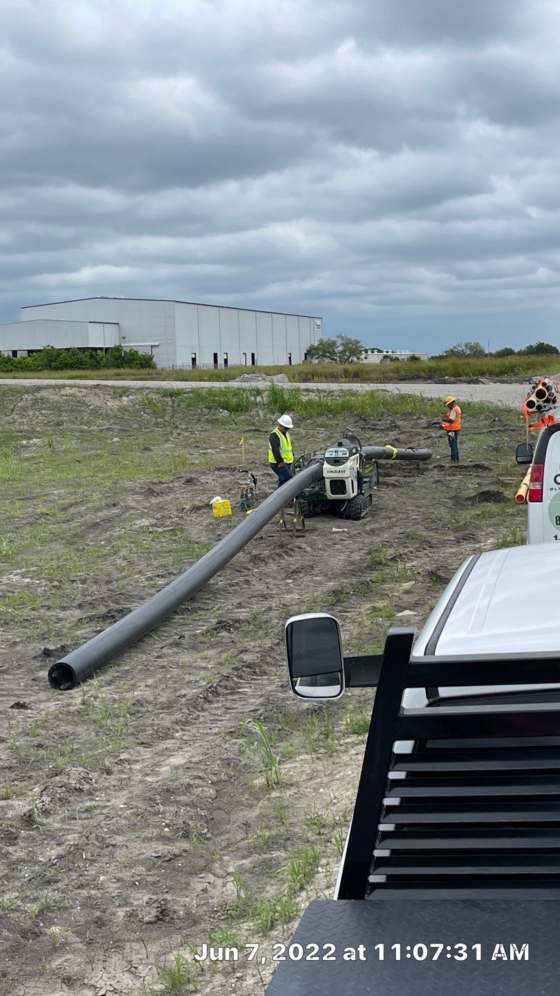 A large pipe is being installed in a field next to a truck.