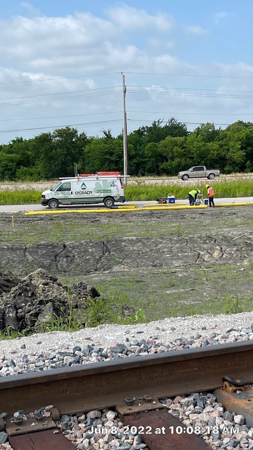 A white van is parked on the side of the road next to train tracks.