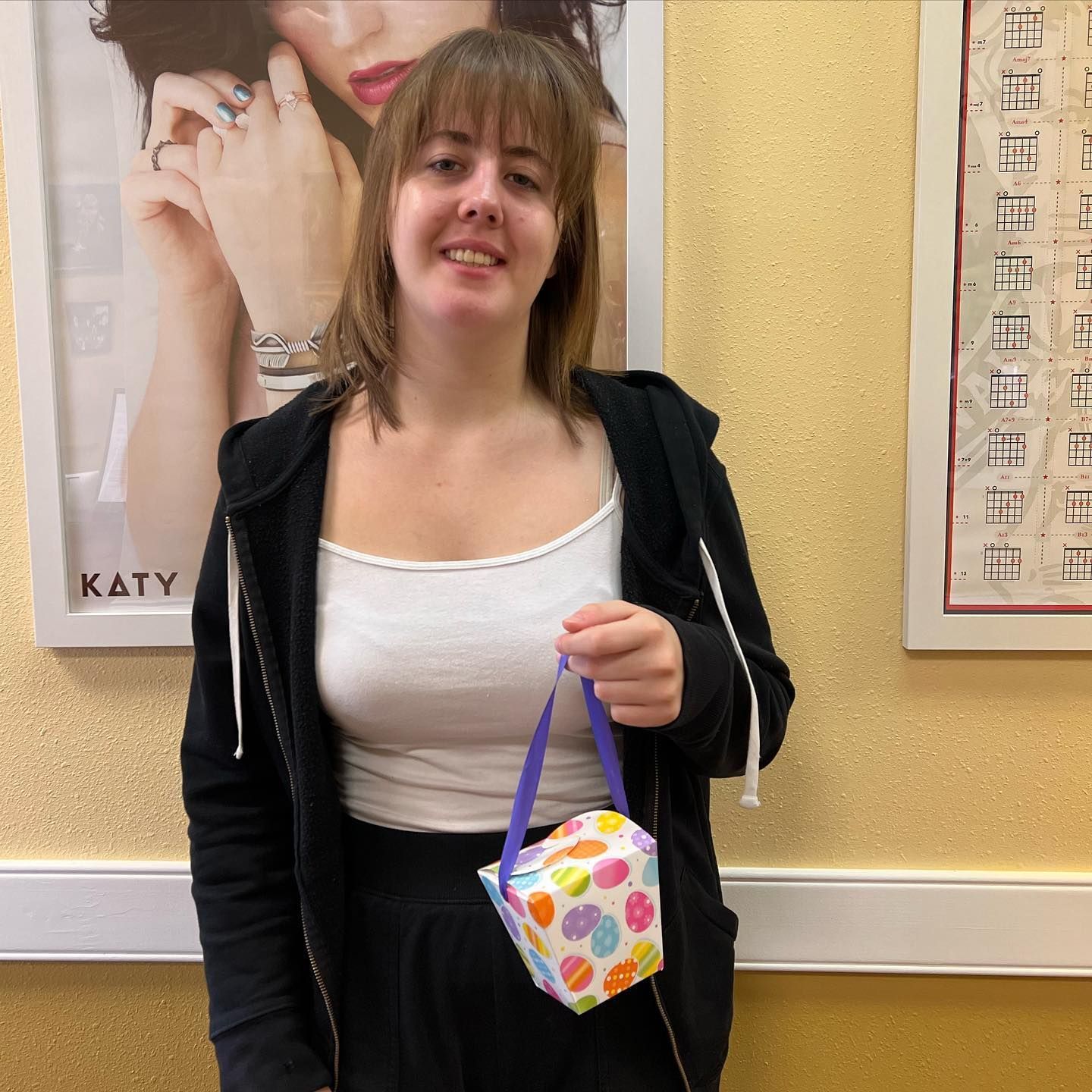 A woman in a black hoodie is holding a polka dot bag