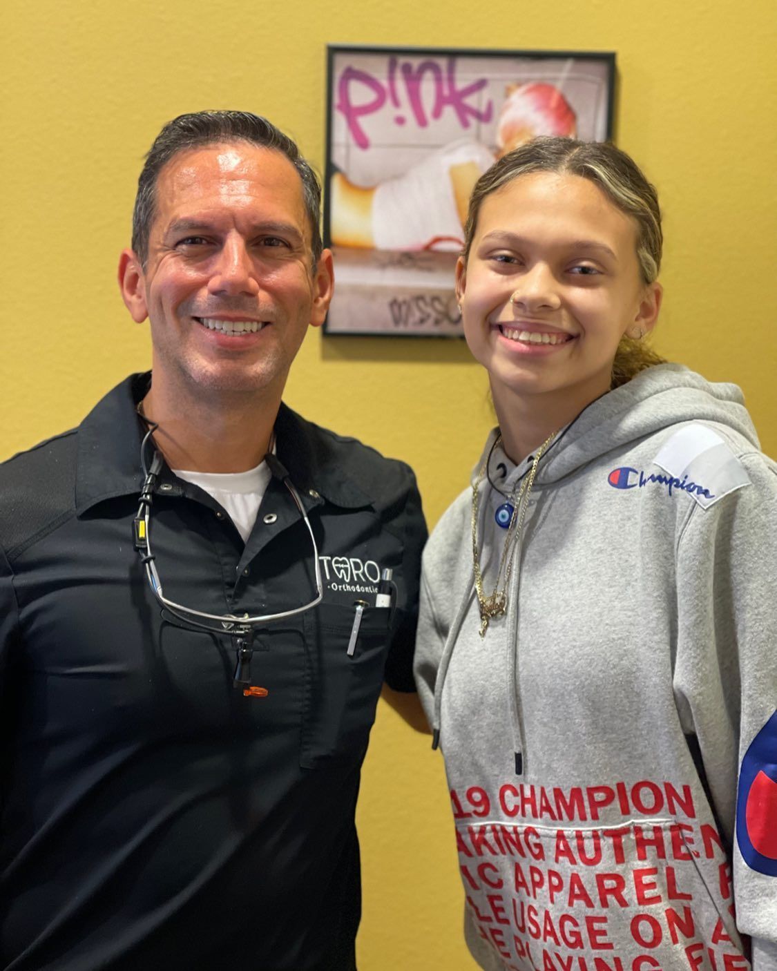 A man and a girl are posing for a picture in front of a pink sign