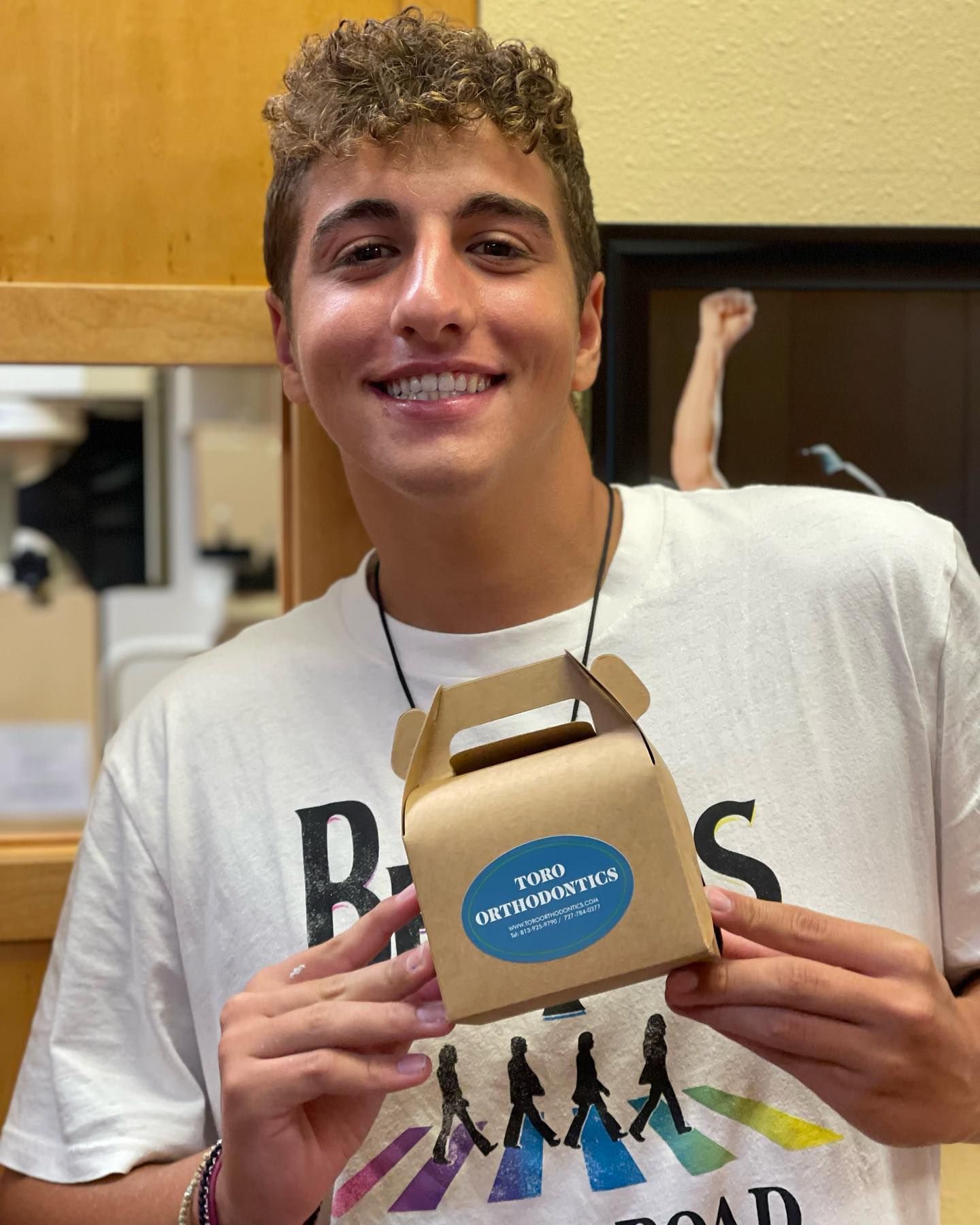 A young man in a white shirt is holding a small box