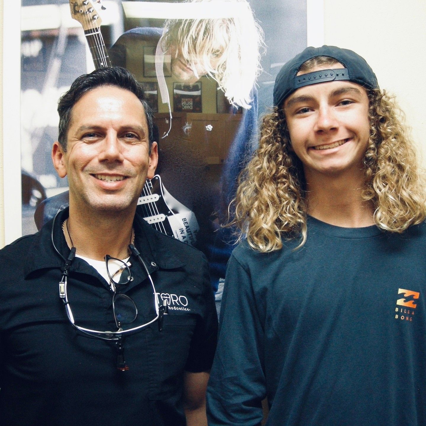 A man and a boy are posing for a picture with a guitar in the background