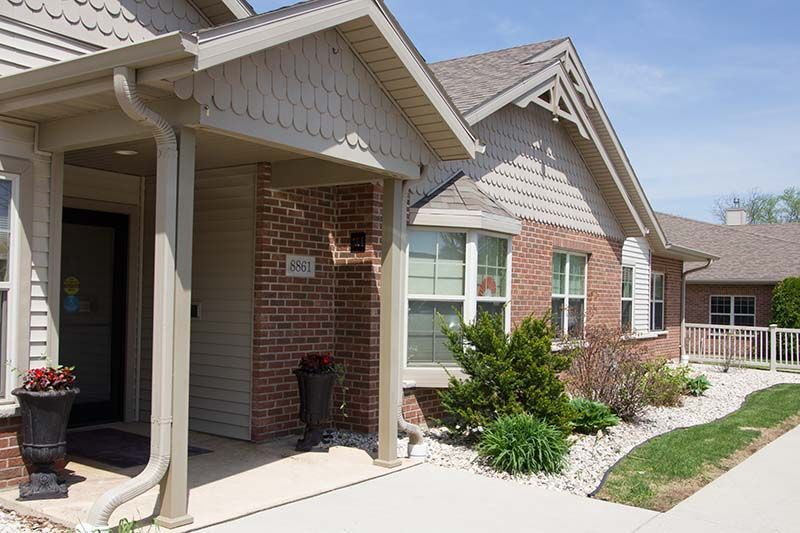 A brick house with a porch and a walkway leading to it.