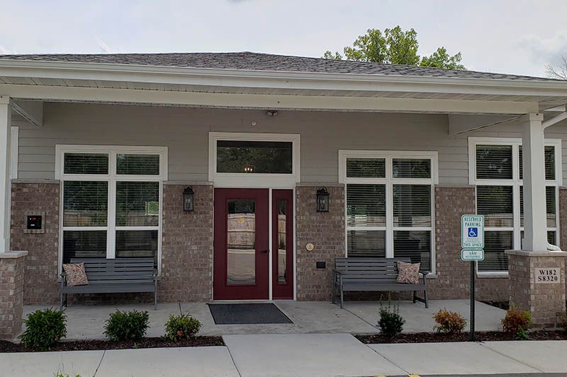 A large brick building with a red door and a porch.